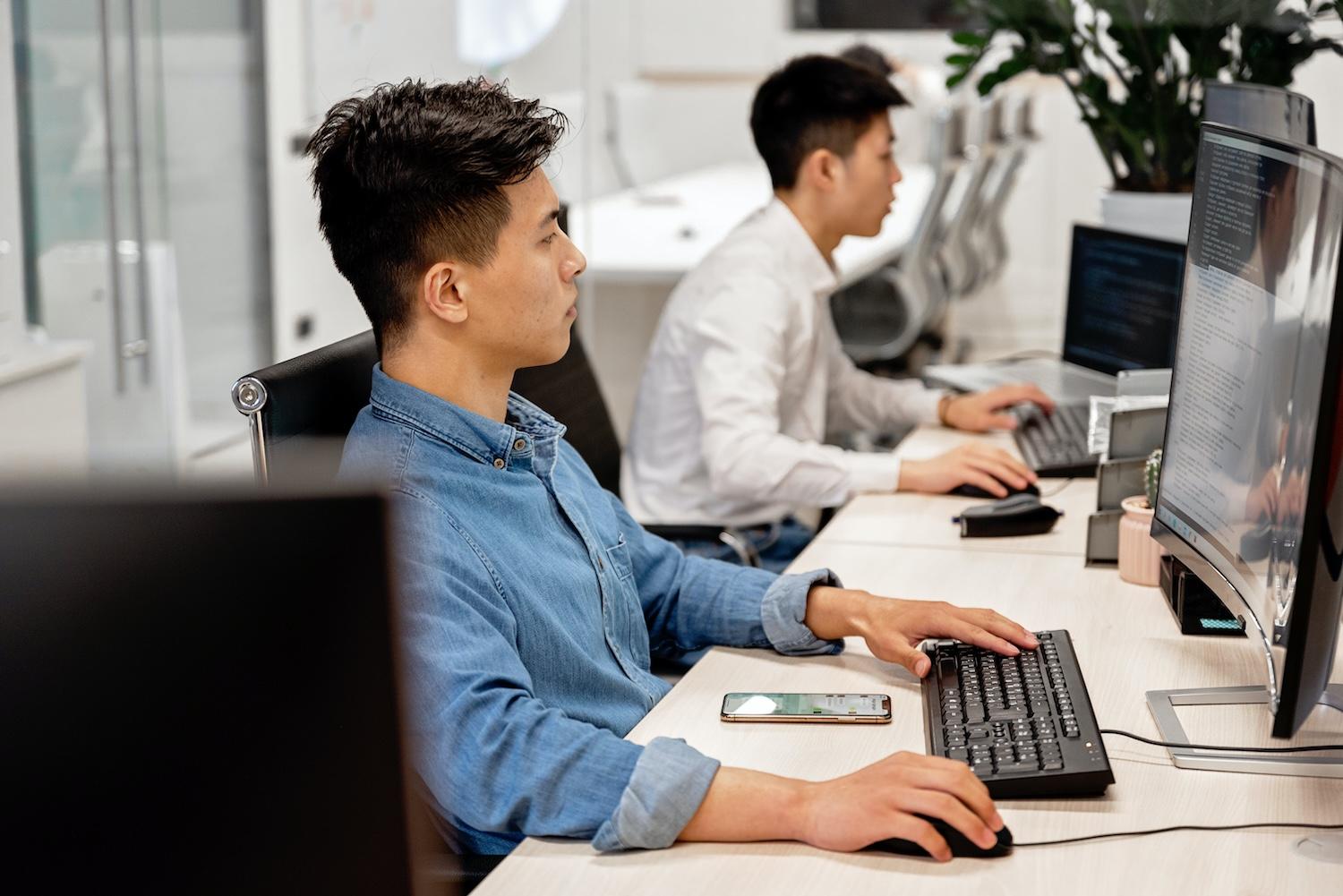 Deux employés devant leurs écrans dans un bureau, représentant l’utilisation quotidienne d’un logiciel CRM