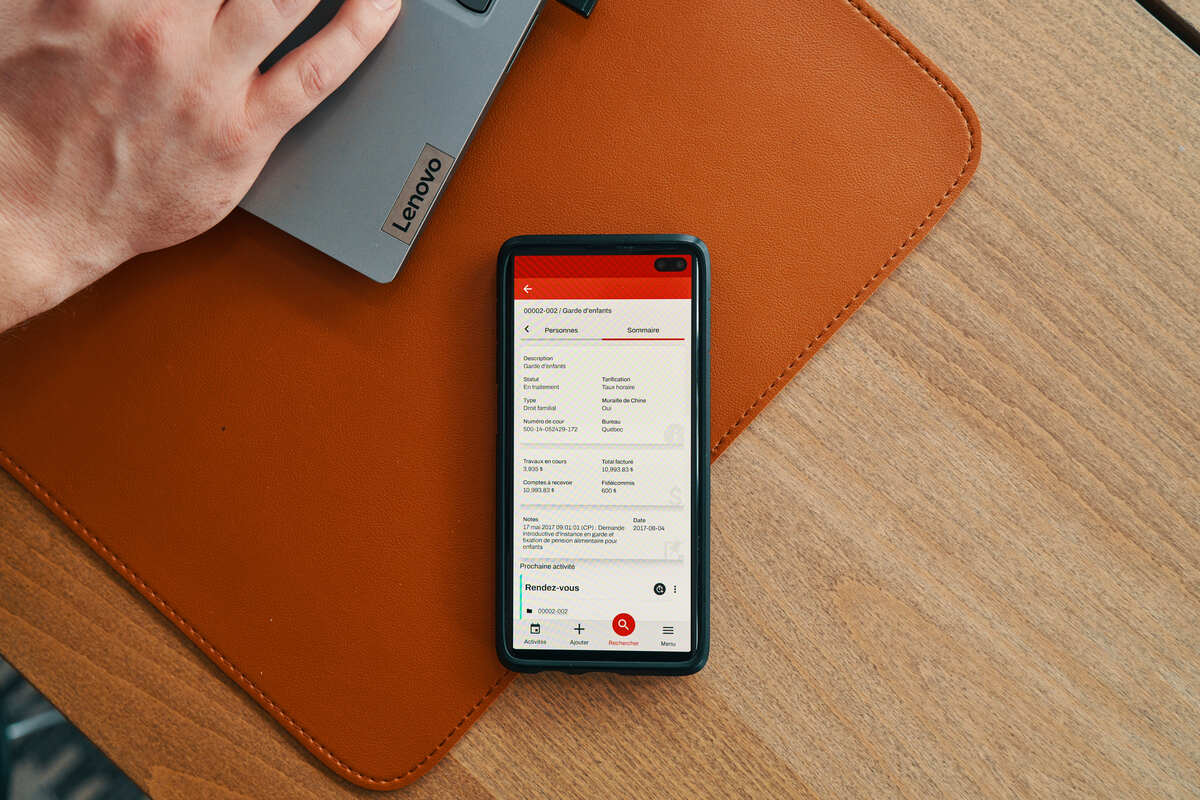 Une fiche de dossier JurisÉvolution affichée sur un téléphone posé sur un bureau